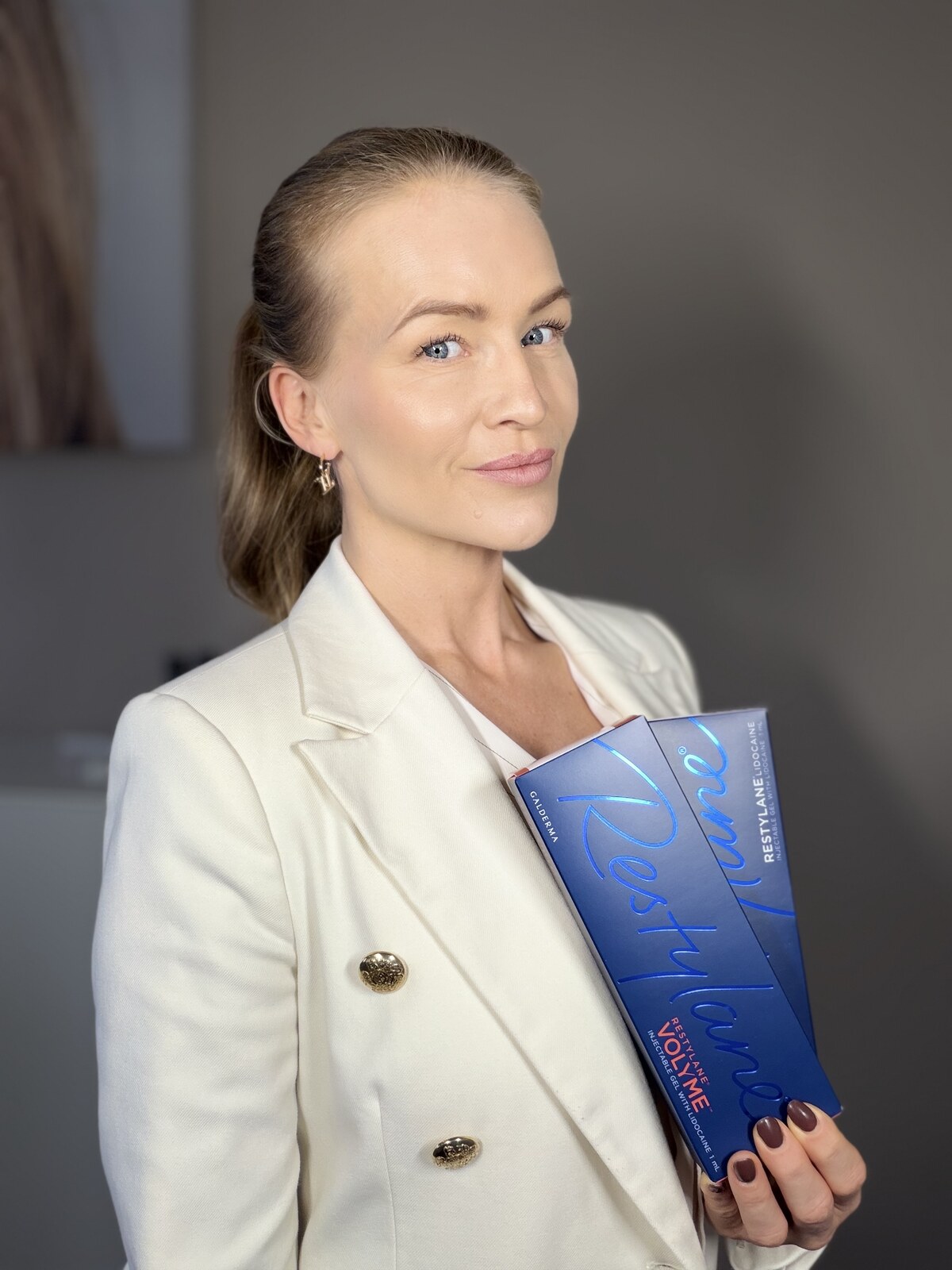 Louise i hvid blazer med Restylane-æsker i hånden